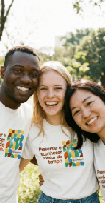 Fotografia de três jovens ao ar livre, próximos e sorrindo para a câmera