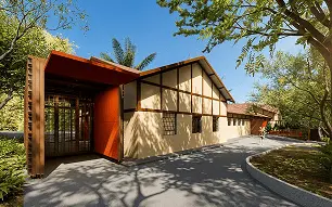 Vista externa do edifício. Estrutura em cor laranja à esquerda, formando espaço coberto com fechamento móvel. 